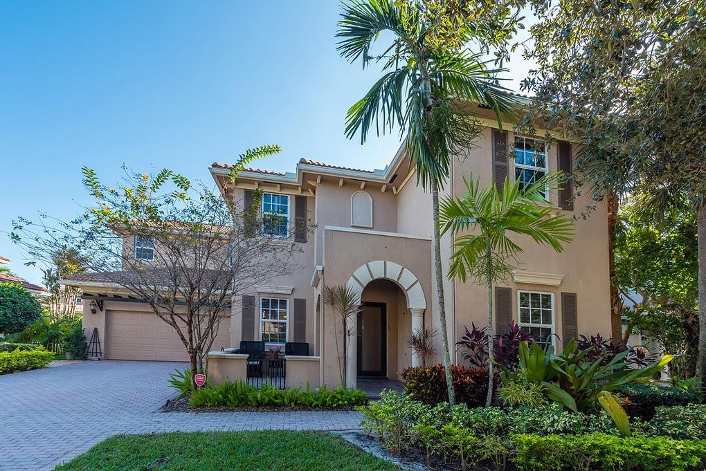 Image of a Florida two-story home, with palm trees in the front yard.
