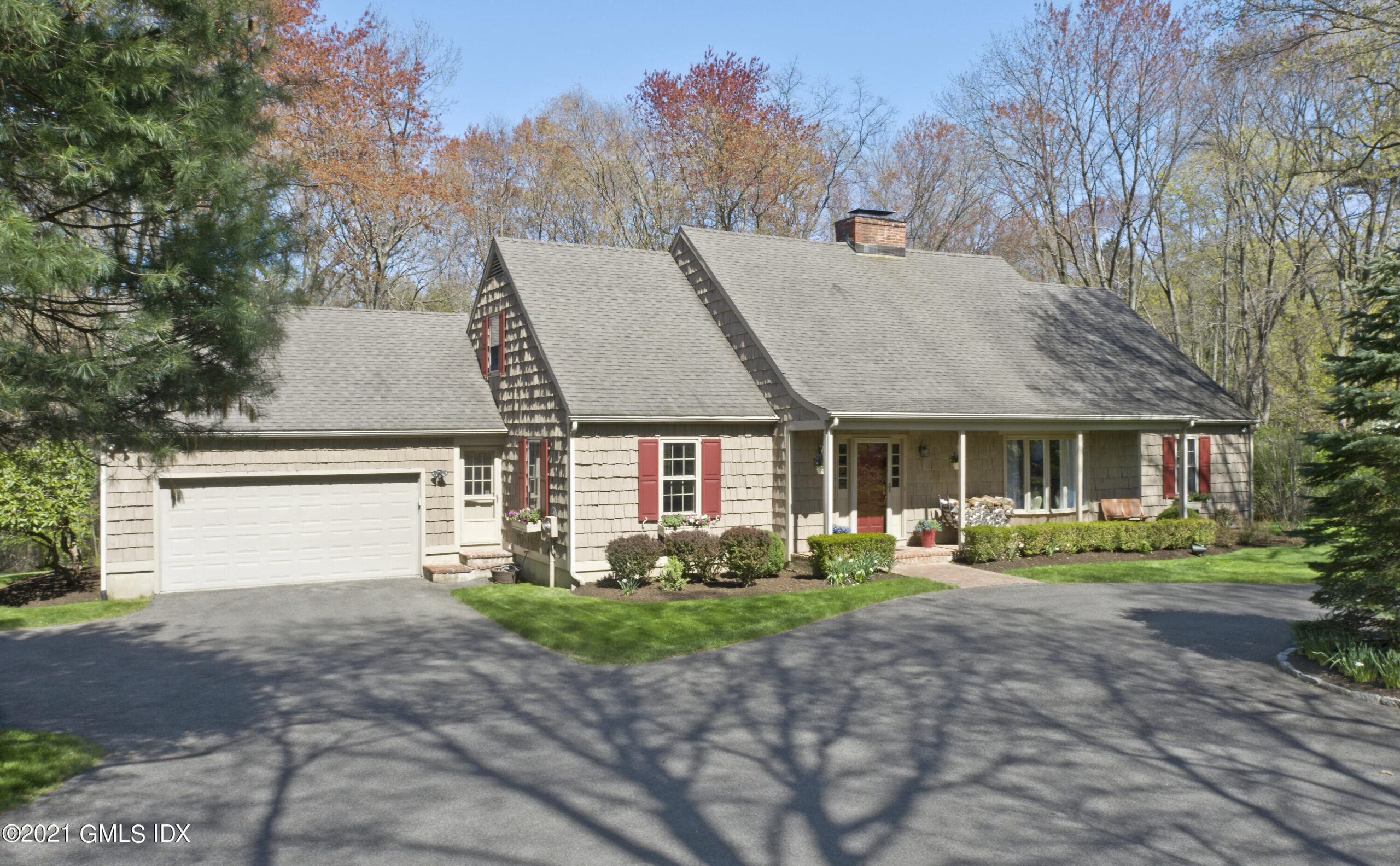 View of home, with red shutters and tan shingles